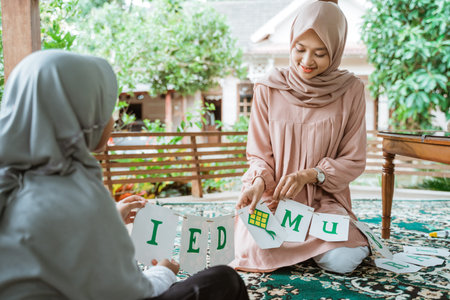 Mother and daughter wearing hijab make flag chain paper decorations