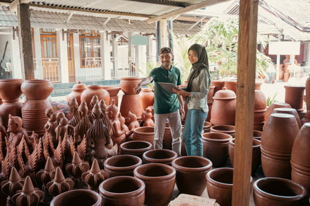 craftsman with pointing finger showing pottery crafts to veiled womanの写真素材