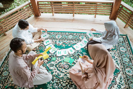 Father, mother and children make flag chain paper decorations togetherの写真素材