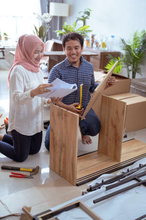 muslim couple assembling new furniture together at homeの写真素材