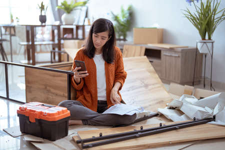 frustrated asian woman while assembling new furnitureの写真素材