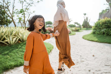muslim mother and daughter walking and hold hand togetherの写真素材