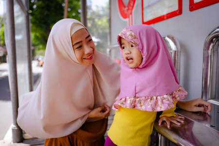 little girl with hijab waiting at metro station togetherの写真素材