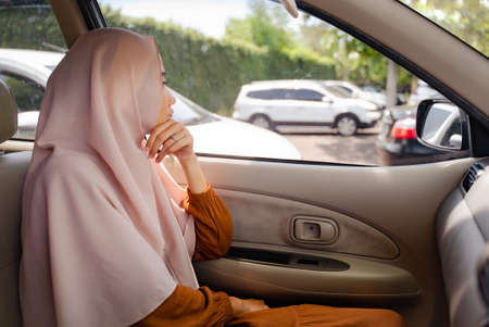 muslim woman sitting on passenger seat and looking outsideの写真素材