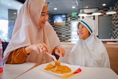 mother and daughter eating pancake. muslim asian family having breakfastの写真素材