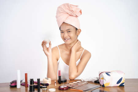 asian girl applying facial moisturizer while holding jarの写真素材