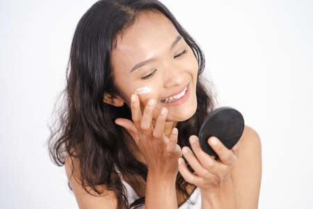 woman applying make up powder and blush on her cheeksの写真素材