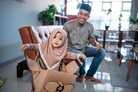 cute toddler playing with cardboard airplane with her fatherの写真素材