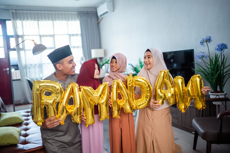 family wearing muslim traditional clothes holding a text of ramadan