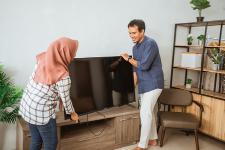 muslim Couple Carrying Flat Television Screen In Their Modern Houseの写真素材