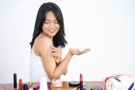 young woman applies cream on her arm. On a white background.の写真素材