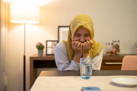 impatient muslim woman waiting to break her fastの写真素材