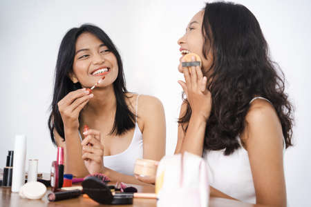 two asian beautiful happy friend while doing make upの写真素材
