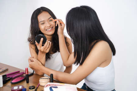 two asian beautiful happy friend while doing make upの写真素材