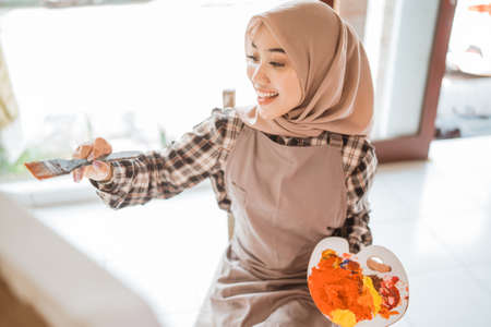 muslim painter is painting in her workshop excitedlyの写真素材