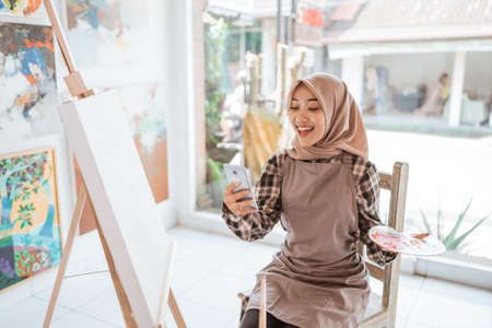 muslim female artist looking for inspiration from her mobile phoneの写真素材