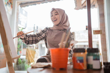 muslim painter is painting in her workshop excitedlyの写真素材