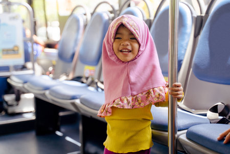 muslim little girl with hijab riding busの写真素材