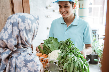 Deliveryman in uniform gives order of fresh vegetables to customer