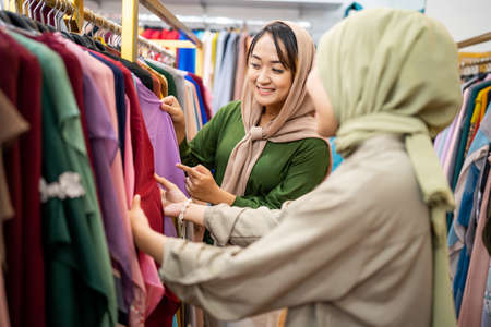 Beautiful muslim female with head scarf looking at a dressの写真素材