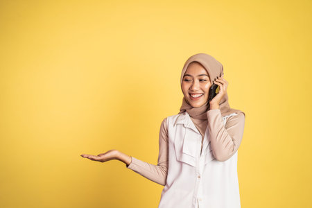 sian woman making a call using a cell phone and presenting copy space