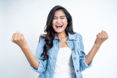 Excited asian woman clenching hands while celebrating successの写真素材