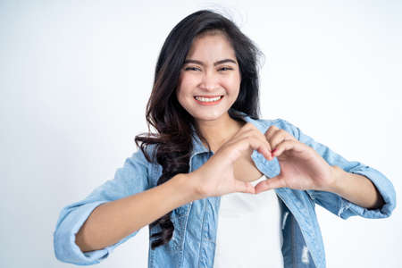 young asian woman smiling in heart shape with fingersの写真素材