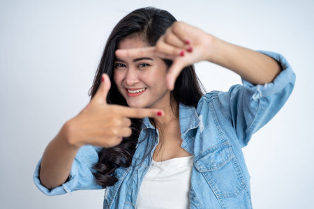 young woman looking from between fingers forming a frameの写真素材