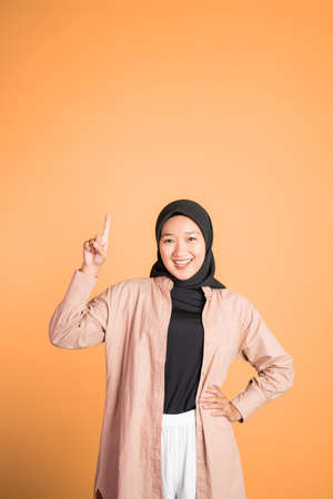 Smiling hijab woman with finger pointing up hand gestureの写真素材