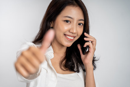 woman making a call using a mobile phone with thumbs upの写真素材