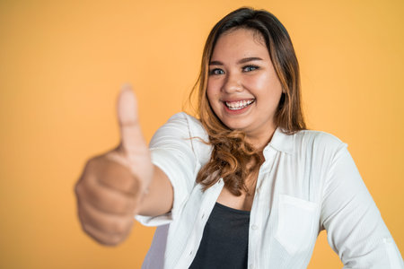 smiling young woman stand with thumbs up on isolated background