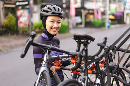muslim female cyclist unloading her road bicycle on a rack in the back of her carの写真素材