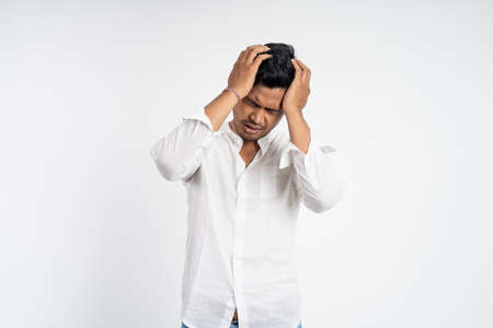 man with both hands holding head while dizzy and depressedの写真素材