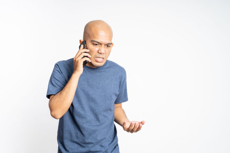 Serious asian bald man listening while calling
