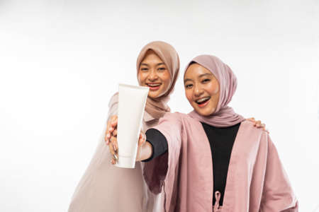 two muslim beauty friend holding a tube cosmetic product for skincareの写真素材