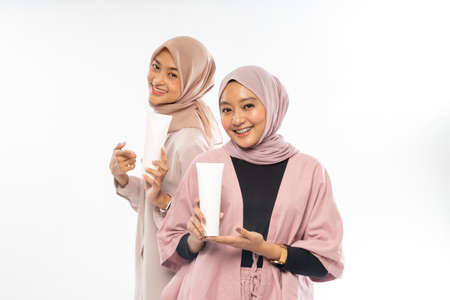 two muslim beauty friend holding a tube cosmetic product for skincareの写真素材