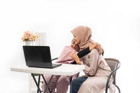 female muslim comforting her sad friend while working on her laptopの写真素材