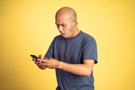 Wondering asian bald man looking at smartphone