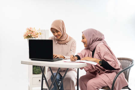 female muslim with hijab working on their laptop togetherの写真素材