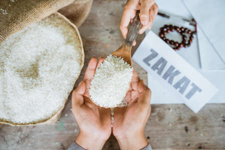 Hands giving rice grains for zakat helping the poorの写真素材