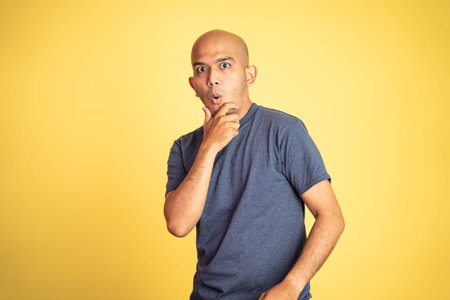 amazed asian bald man with hands holding mouth