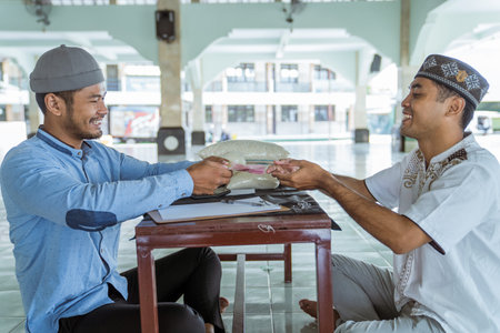 muslim paying some zakat charity using cash at the mosque