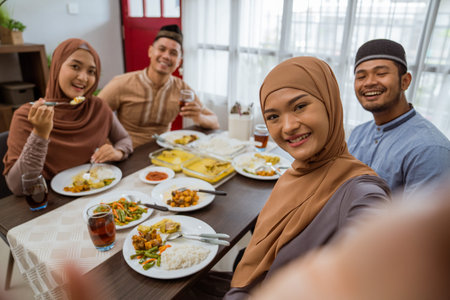 asian muslim friend take selfie together with smartphone while having iftar dinner