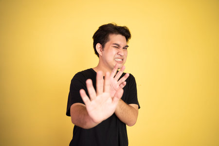 oung man rejecting offer with both palms on isolated background
