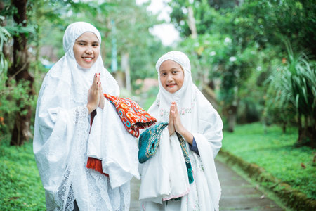portrait of mother and daughter wearing mukena