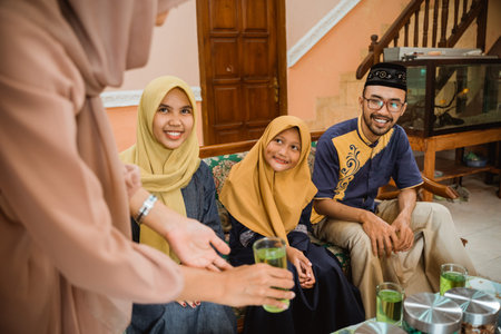 muslim home owner serving her guests with a glass of drink