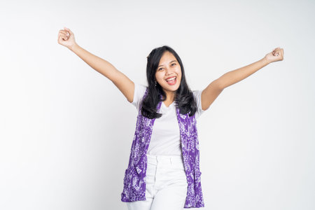 Excited young asian woman clenching hands while celebrating success on isolated backgroundの写真素材