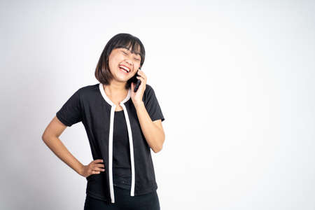 Young asian woman making a call using a cell phone on isolated backgroundの写真素材