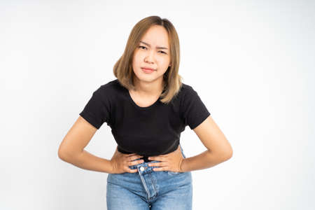 Young asian woman having her period holding her stomach in pain on isolated backgroundの写真素材