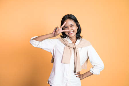 Young asian woman with peaceful hand gesture on isolated backgroundの写真素材